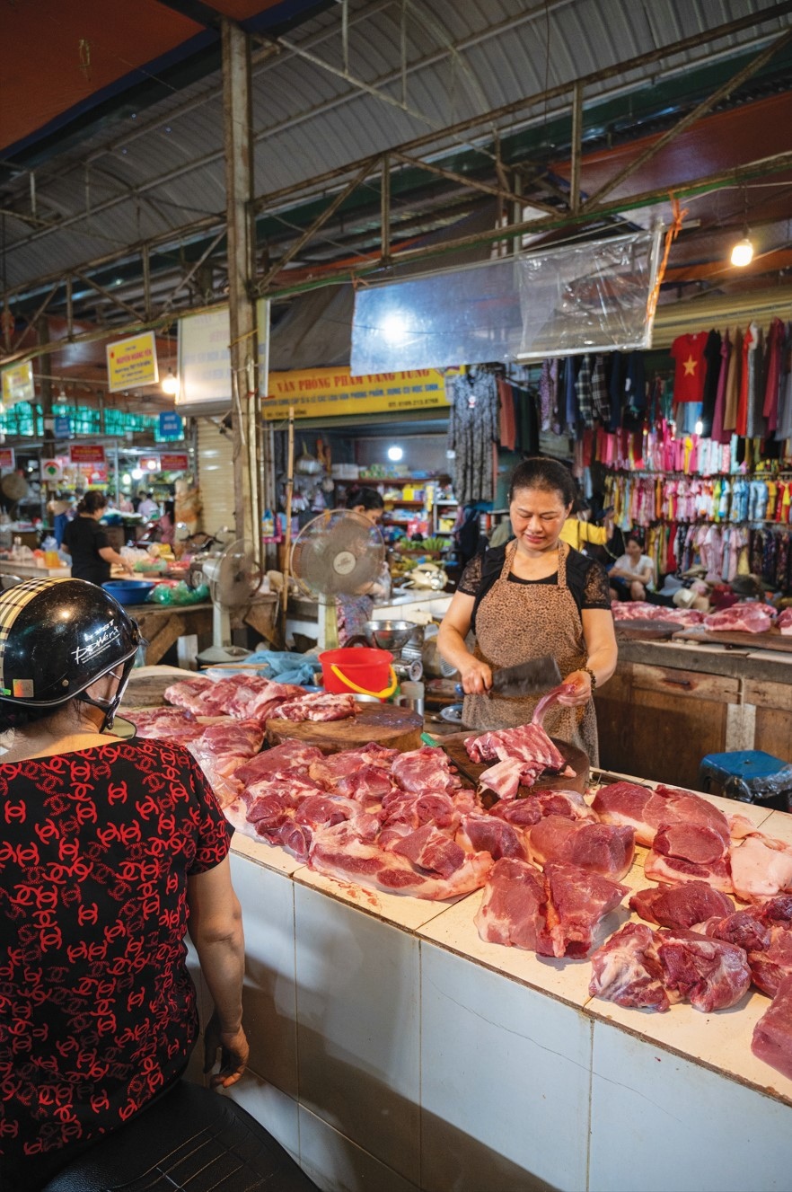 woman in market cutting up meat