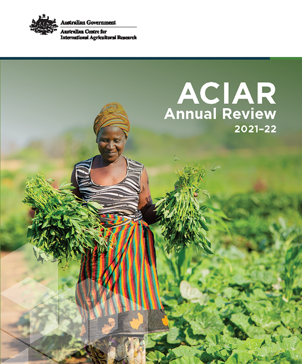 The cover image of the ACIAR Annual Review 21-22 showing a female farmer carrying bunches of freshly harvested vegetables.