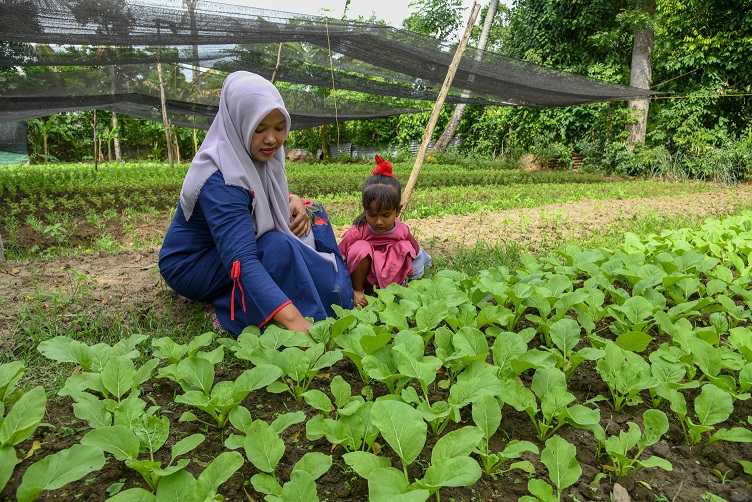 mother and daughter tending crops