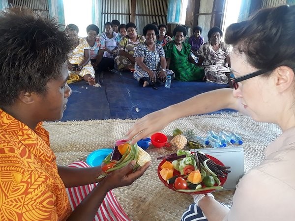 Lydia O'Meara showing a workshop participant in Fiji what foods help make up a healthy diet.