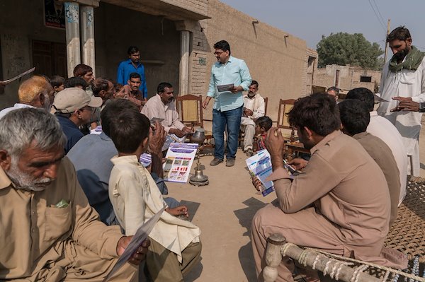 Abdul Aziz from University of Veterinary and Animal Sciences (UVAS) hands out information sheets to the farmers from 96D village in rural Punjab Province. Image: ACIAR/Conor Ashleigh