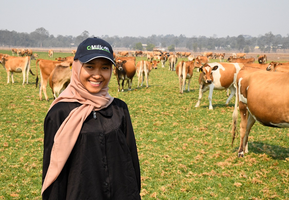 a woman in front of a dairy herd 