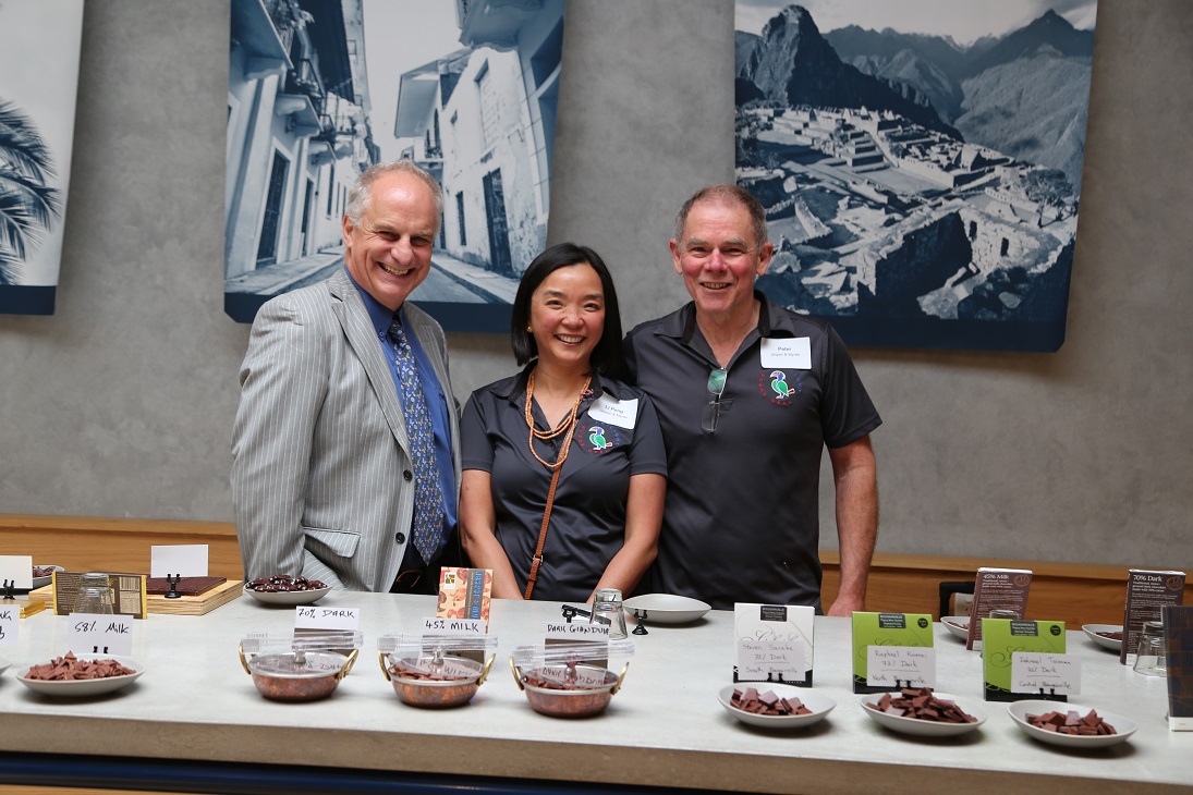 three people behind a table of chocolates