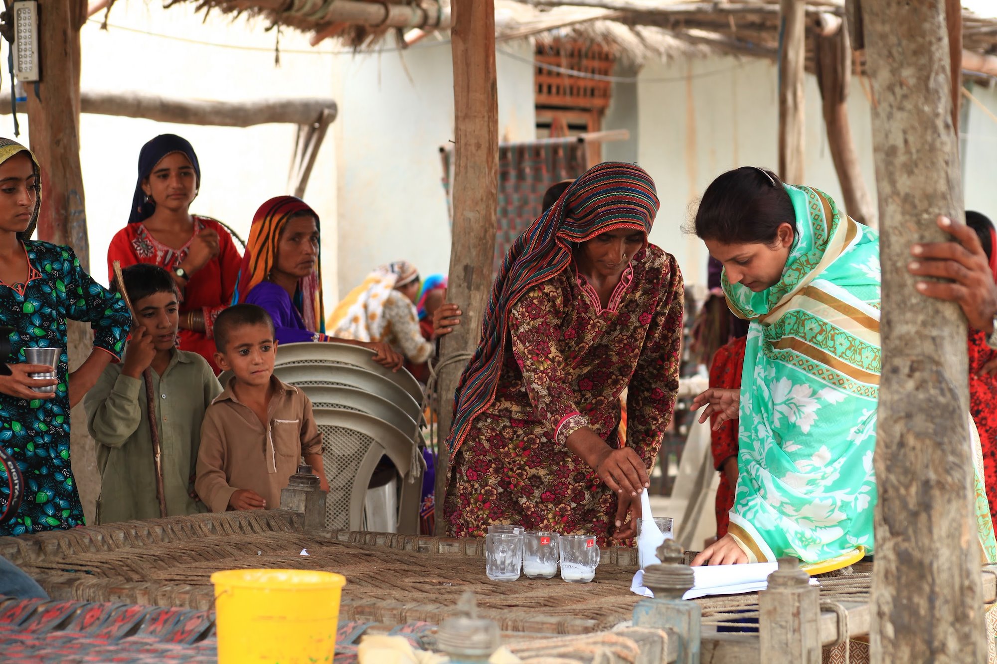 Women and children in a hut putting white substance into a jar