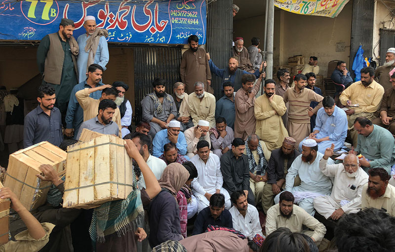 A crowd of men at a fruit auction Pakistan