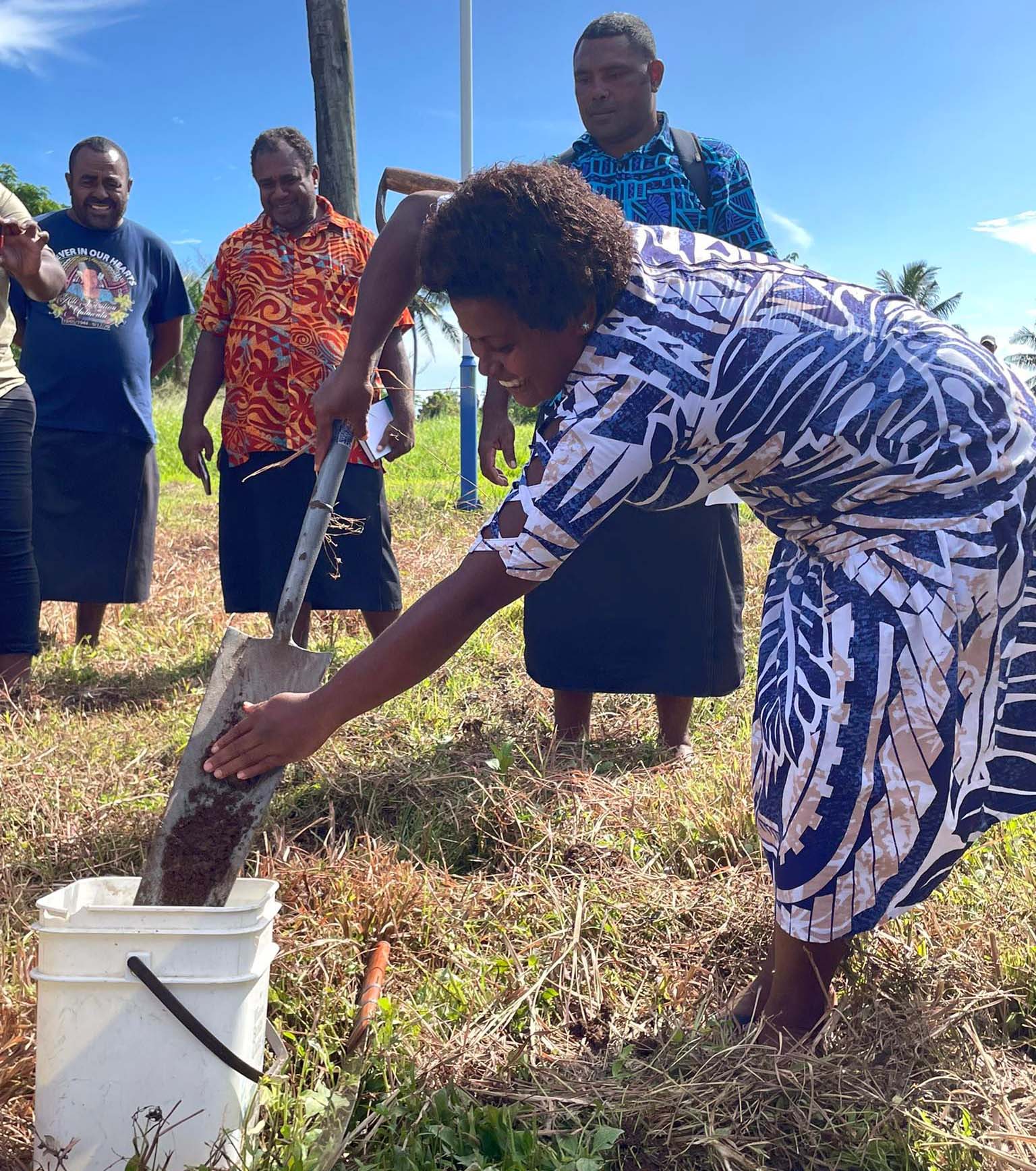 Female farmer shoveling soil into a bucket 