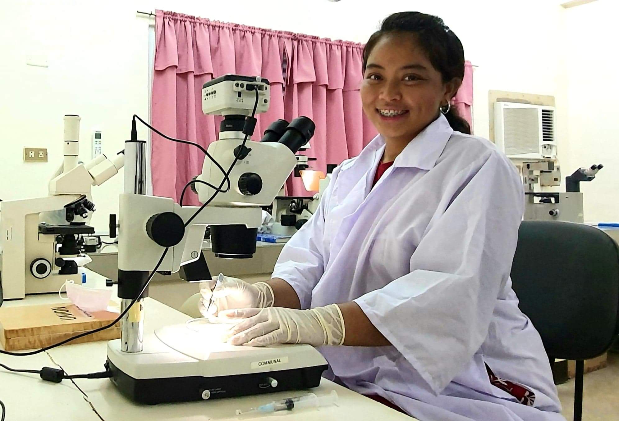 Woman in laboratory sitting in front of microscope