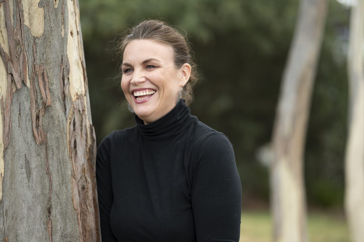 Woman smiling leaning against tree