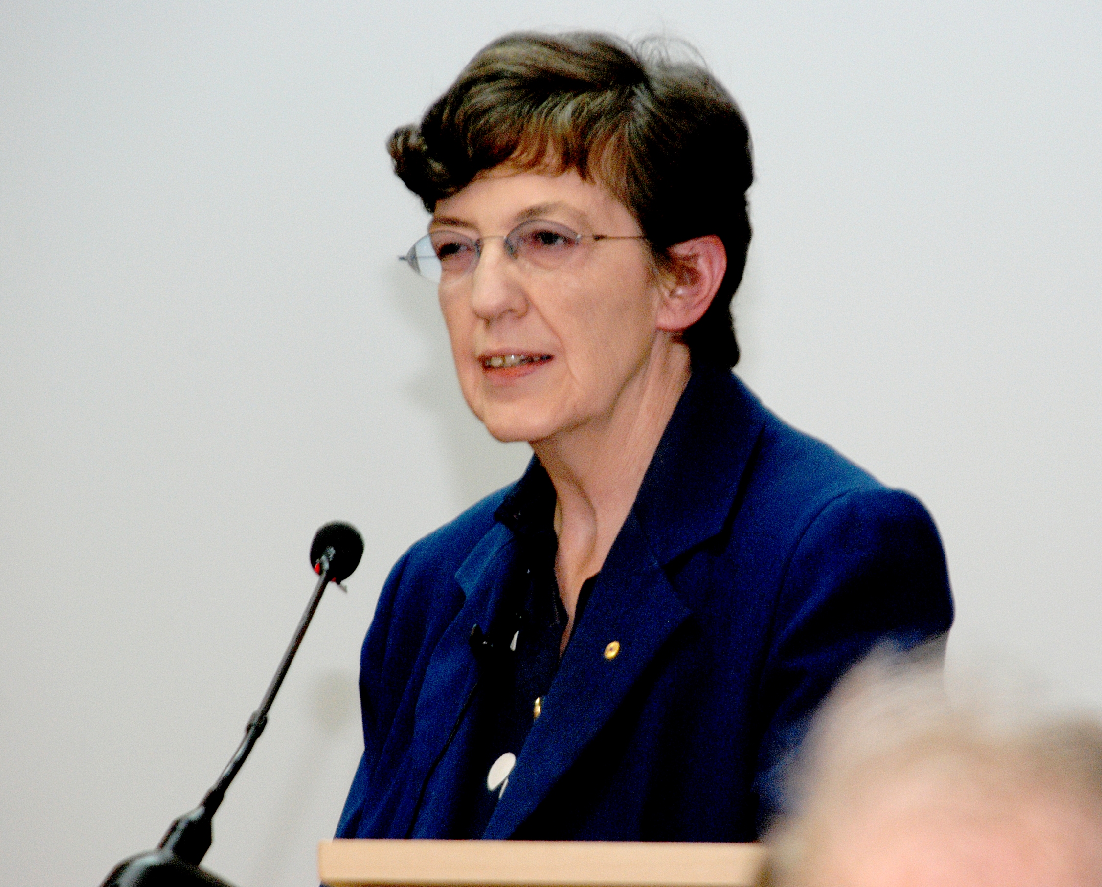 Woman speaking into microphone at lecturn