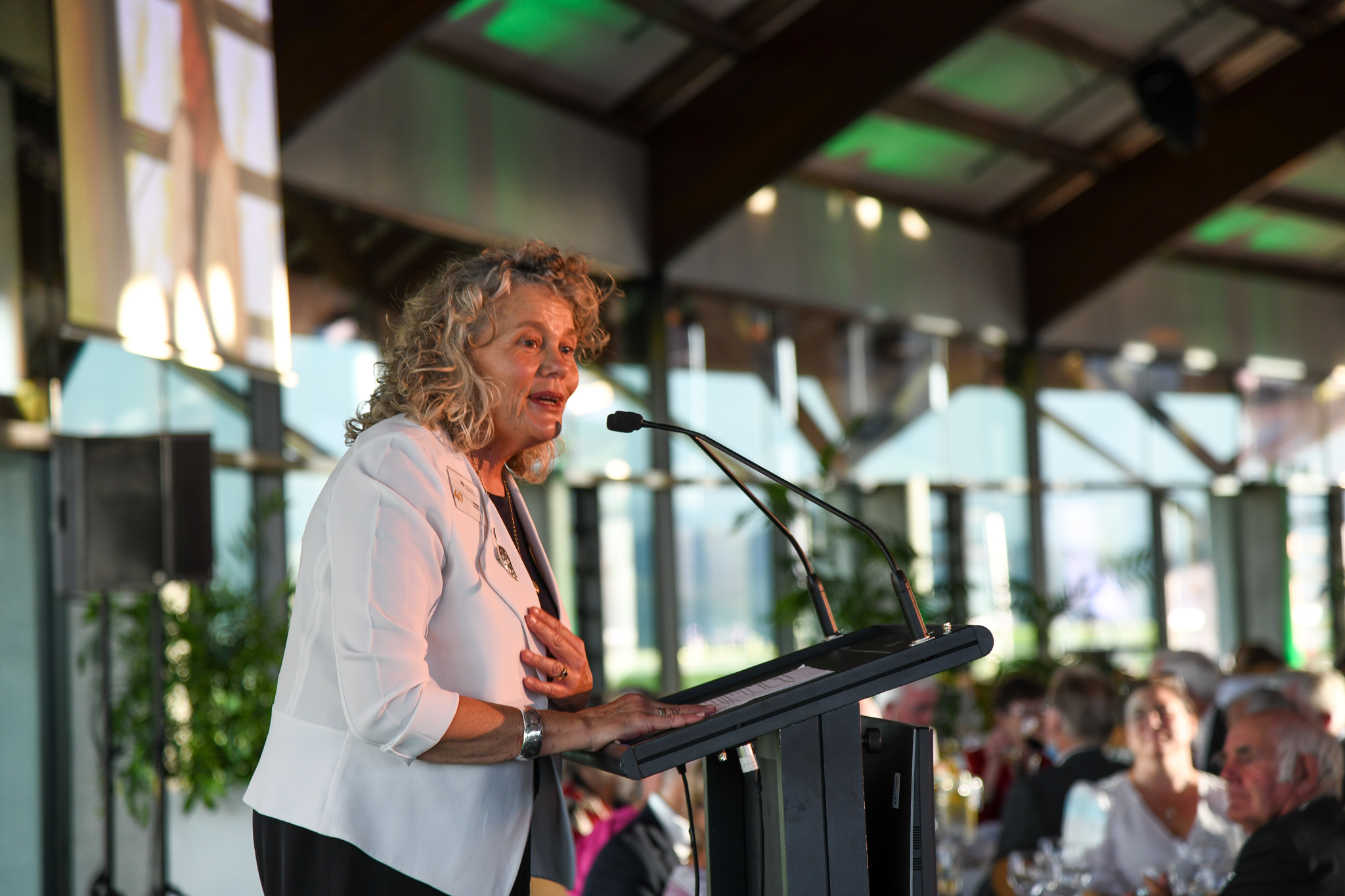 Woman standing talking at lectern to crown