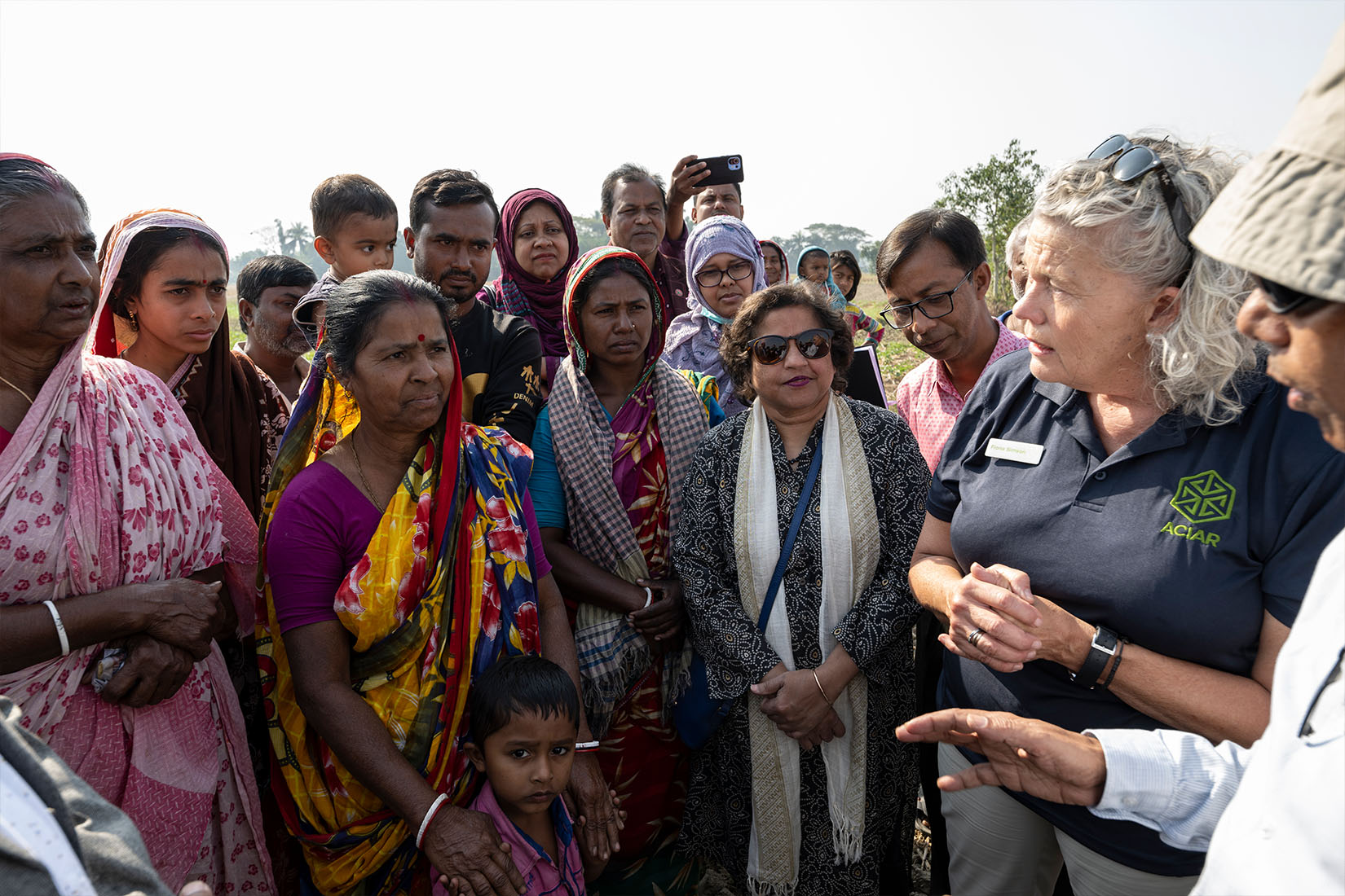 A group of South Asian women speaking with a woman wearing an ACIAR branded polo shirt.