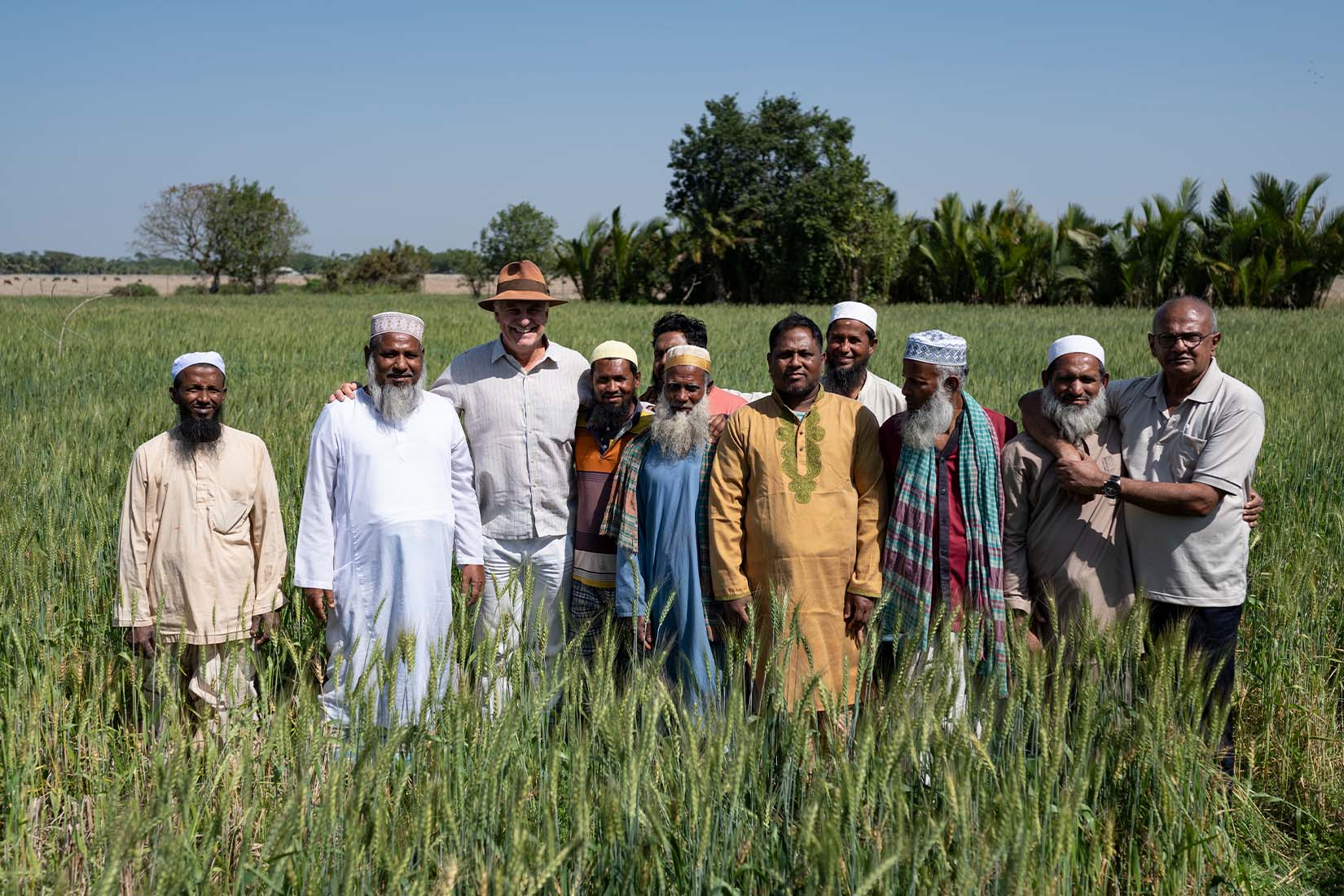 A group of men smiling at the camera in a field.