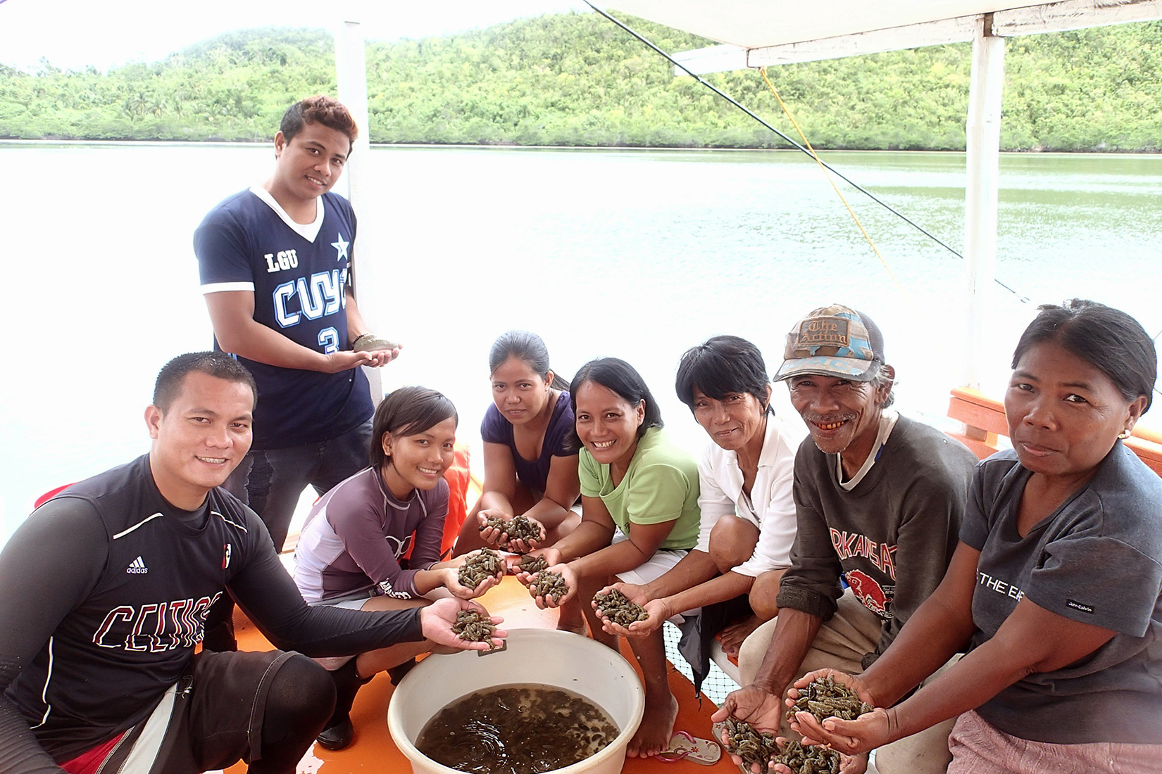 A group of people on a boat holding sea cucumbers