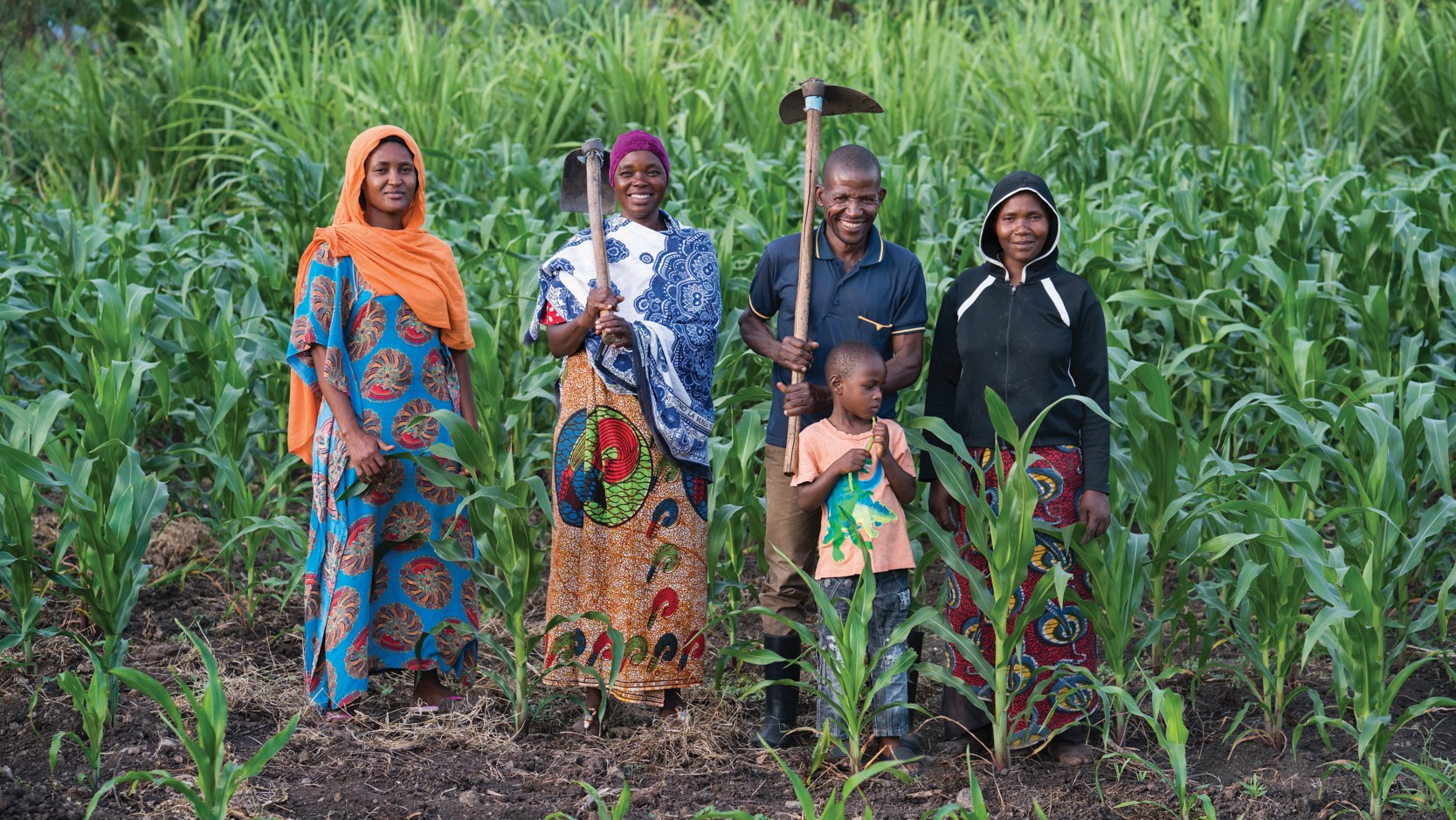 A family of farmers in a field with farming tools