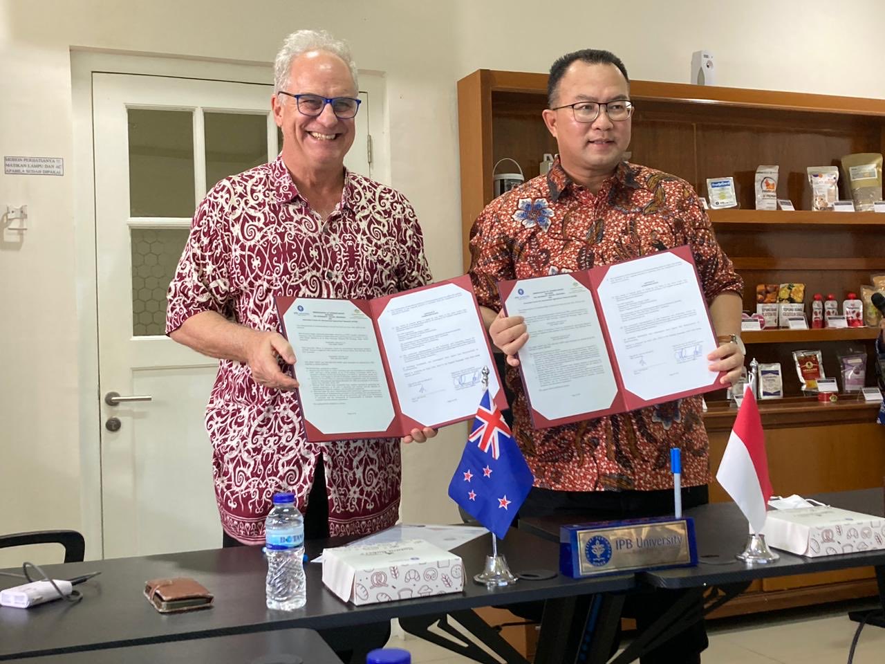 Two men holding up signed agreements.