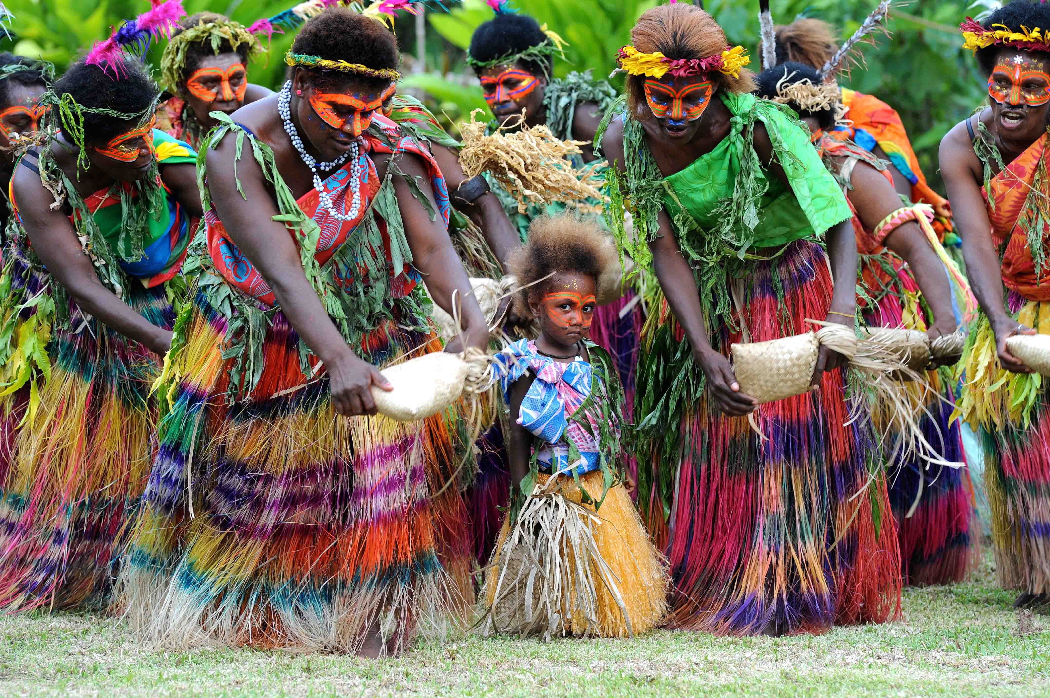 colourful dancers in colourful grass skirts with a small child