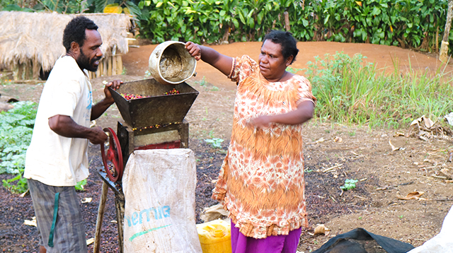 A man and a woman using a grinding machine outdoors.