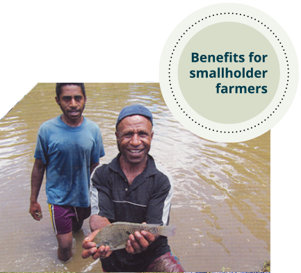 Two men standing in a body of water. One man is holding a small fish and smiling. 