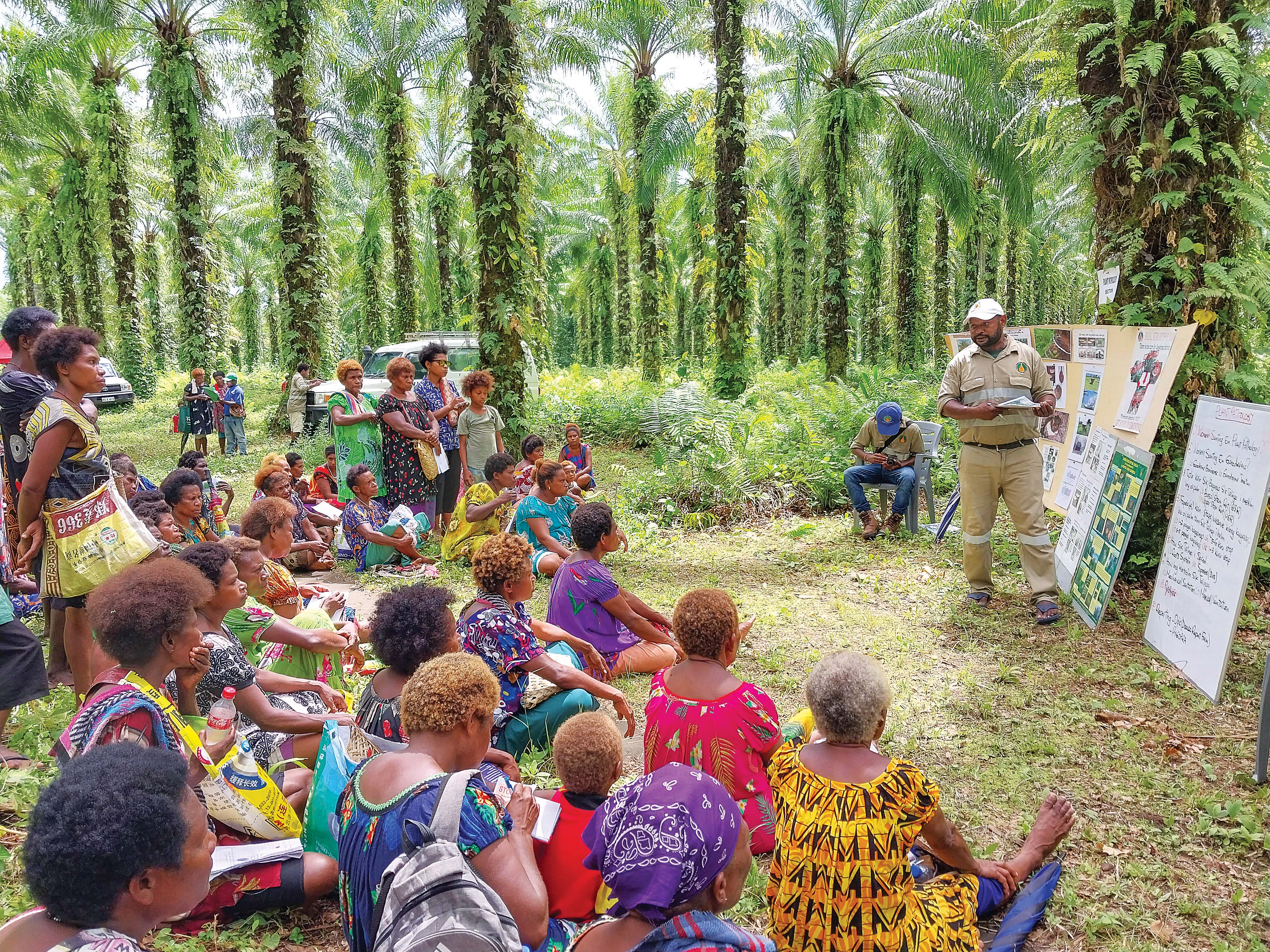 Women farmers watching a man give a presentation.