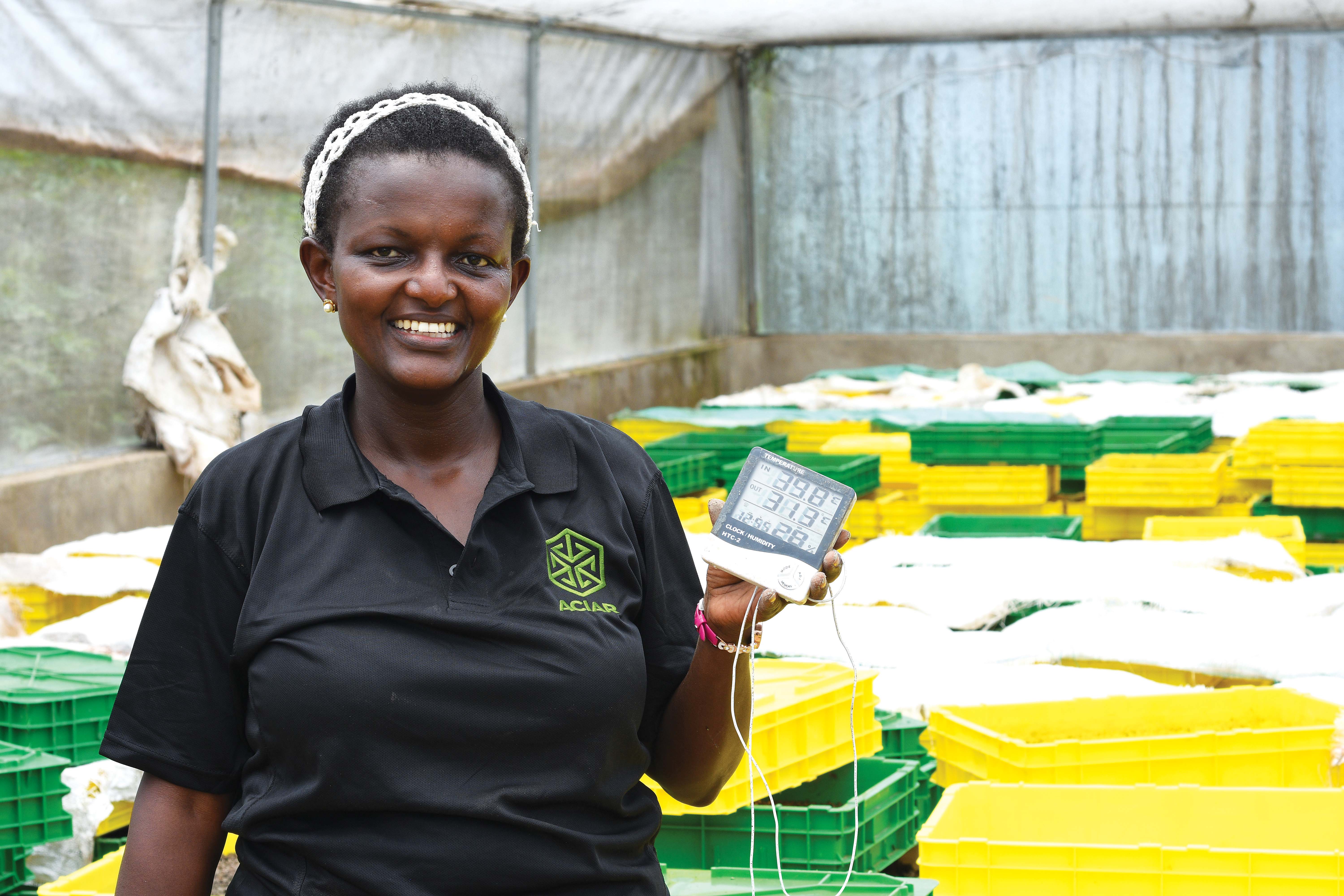 A woman in a black shirt smiling holding a thermometer