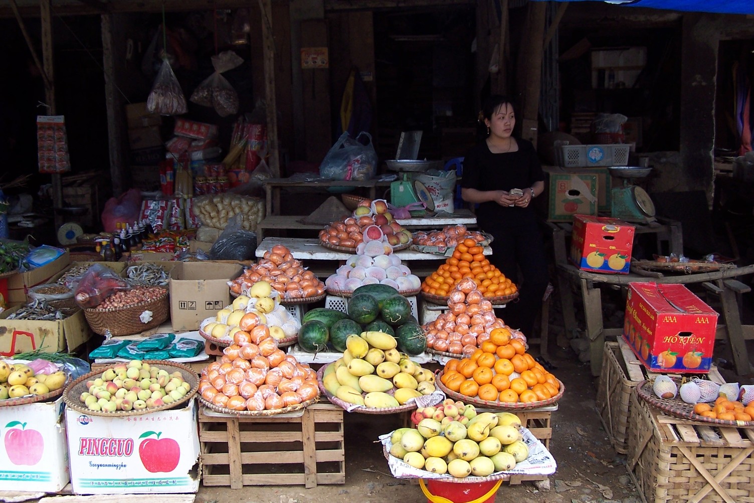 Market vendor standing next to displays of fruit and vegetables