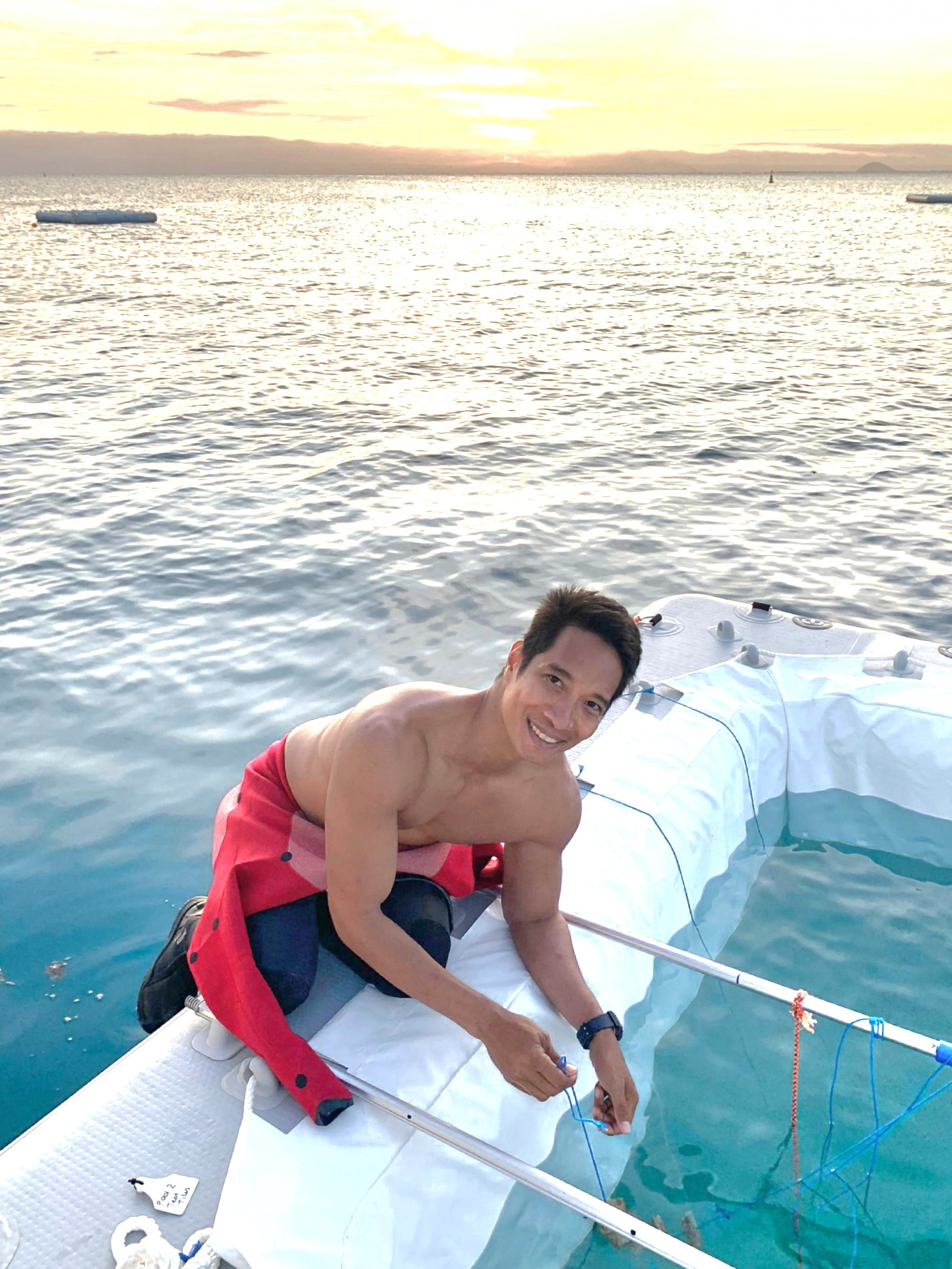 Man sitting on side of fishing raft setting out nets