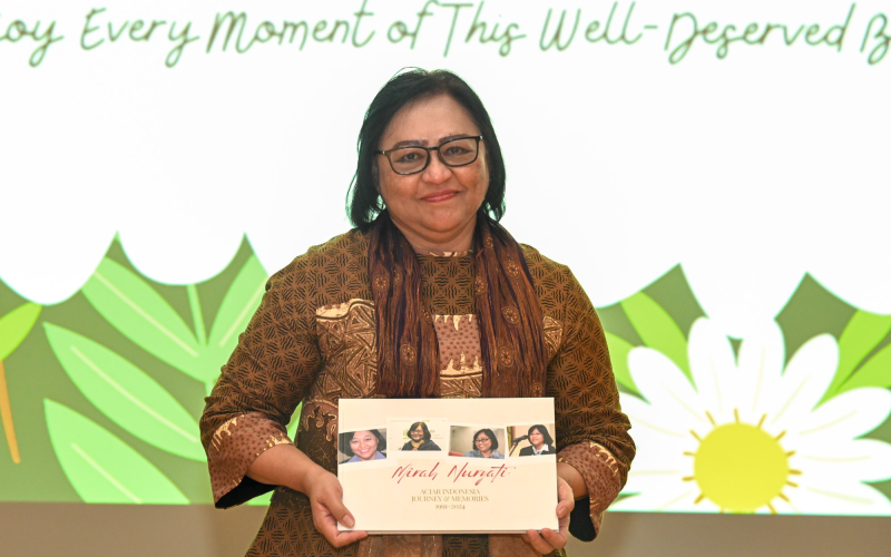 Woman holding a book titled Mirah Nuryati