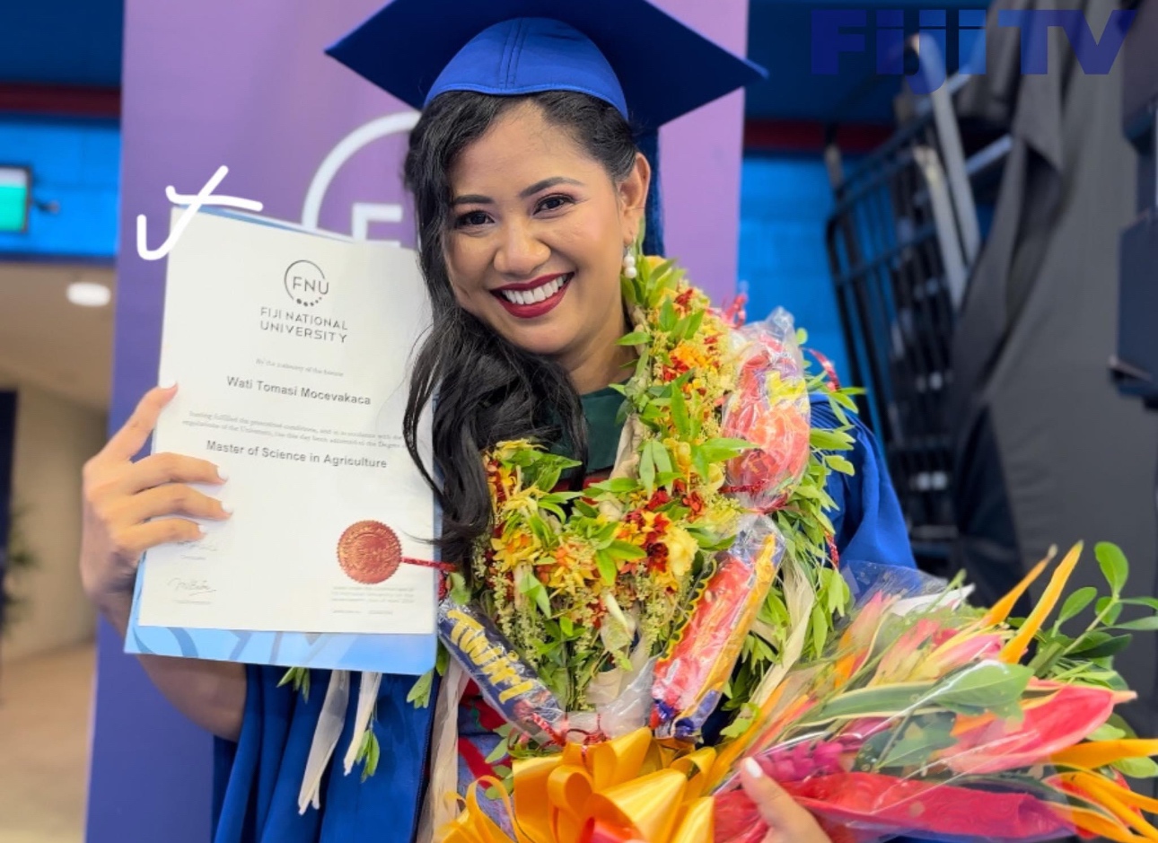 Women smiling in blue graduation attire holding a certificate flowers
