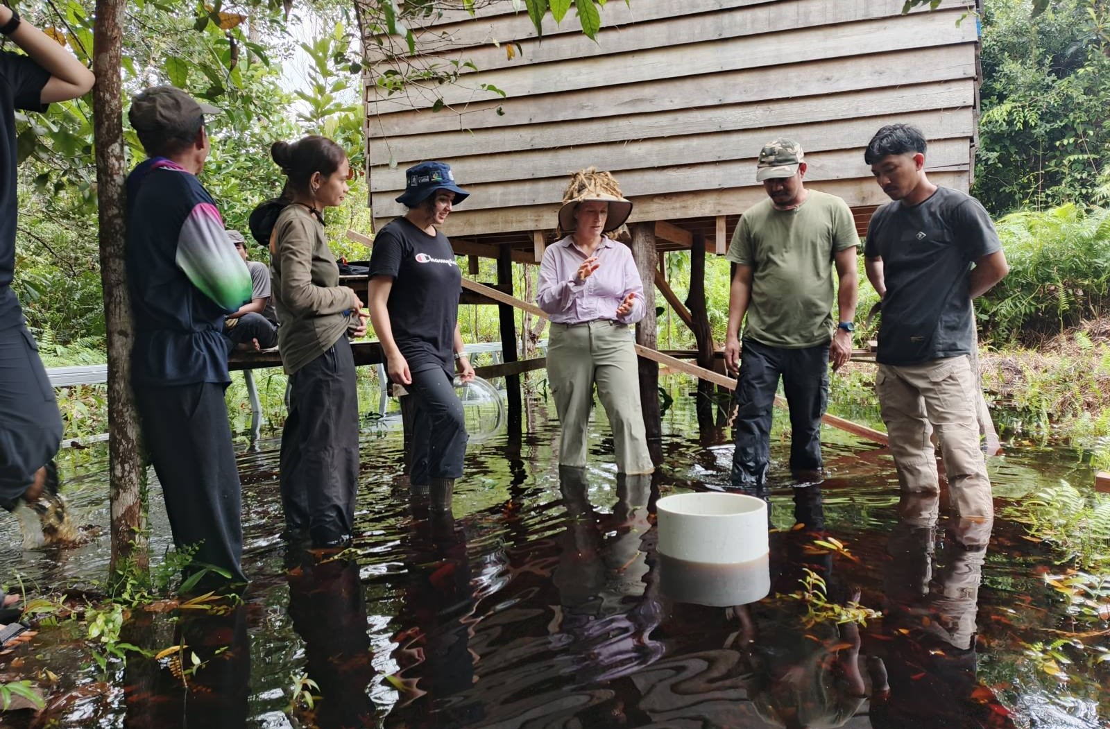 Group of people standing in water around a small structure