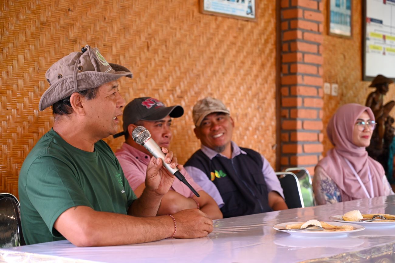 Four people seated at a table speaking into a microphone
