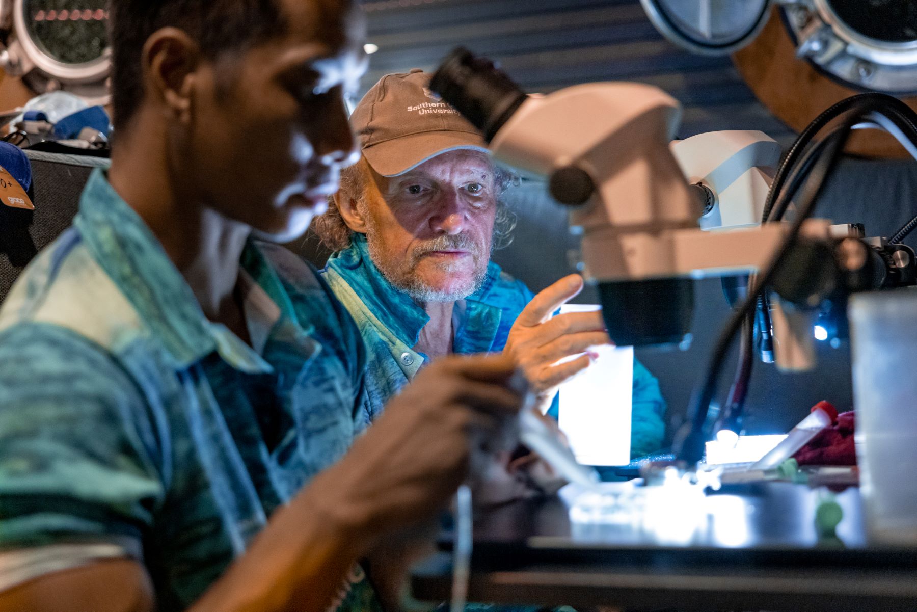 Two men inspecting something under a microscope