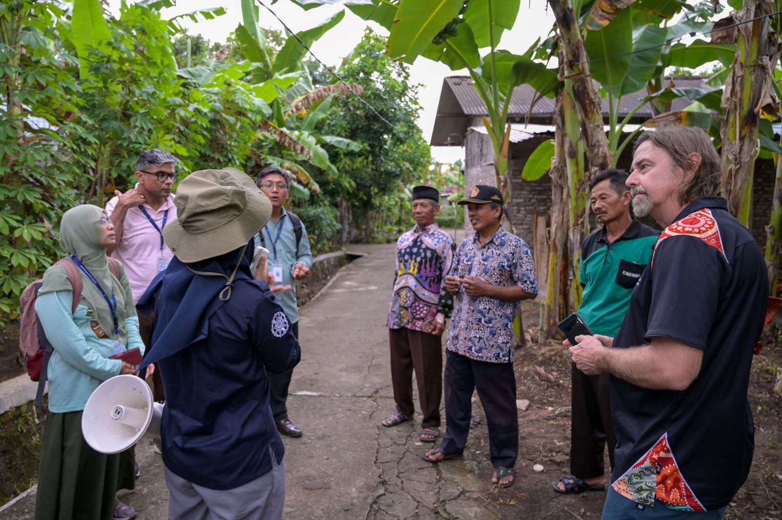 Group of people in discussion standing under banana trees