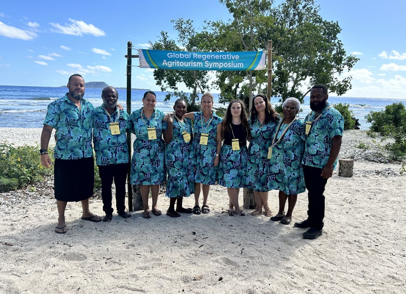 Group of people standing on a beach in front of a banner