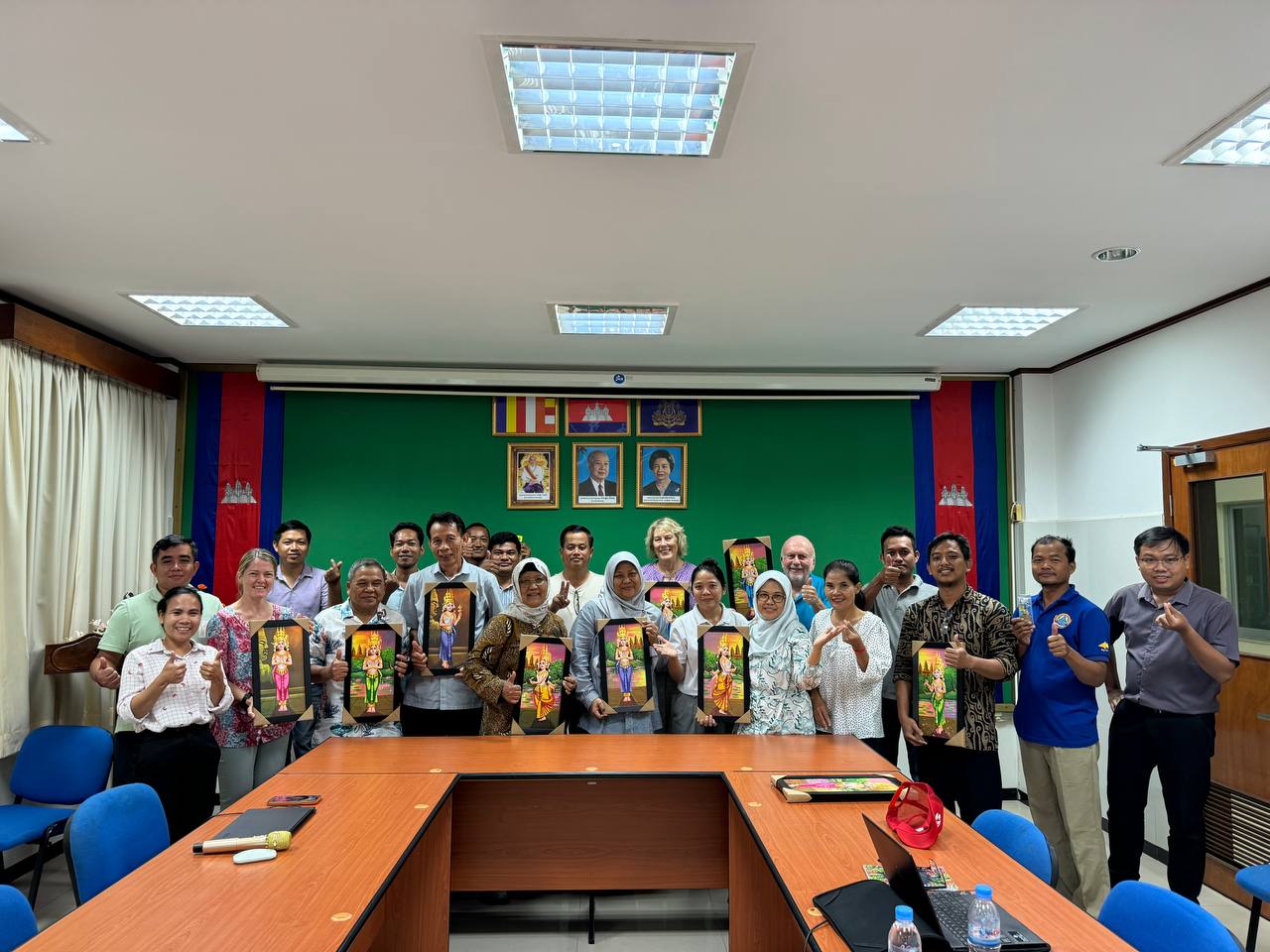 Group of people standing together in a room, holding pictures