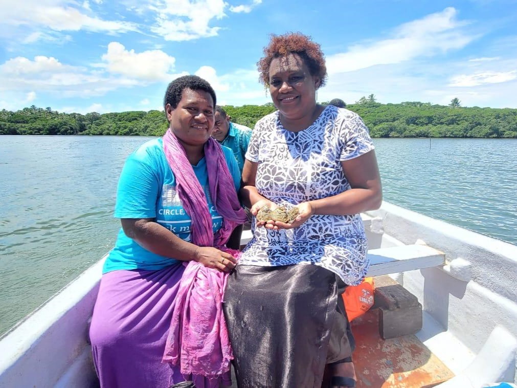 2 people on a boat holding oysters