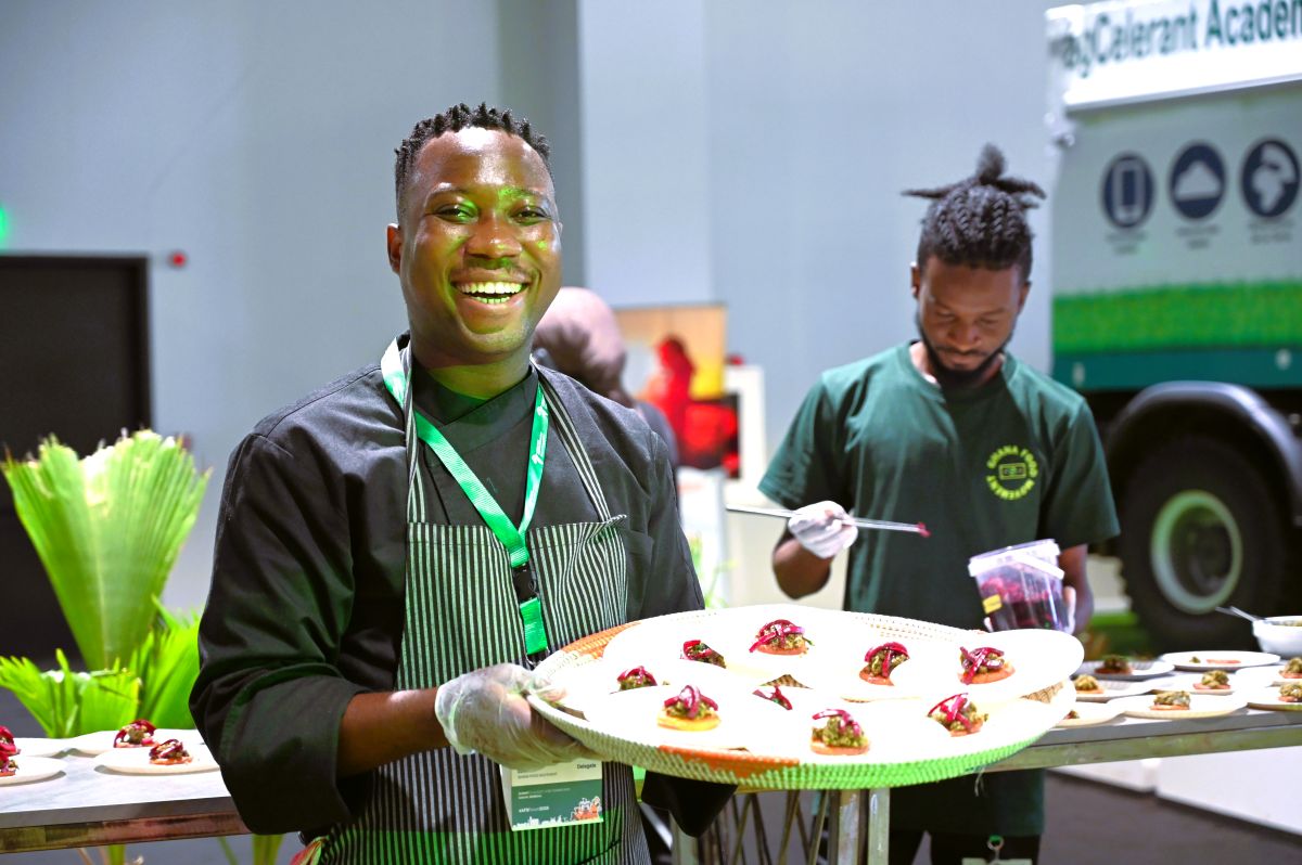 A man wearing an apron and holding a large tray of appetisers