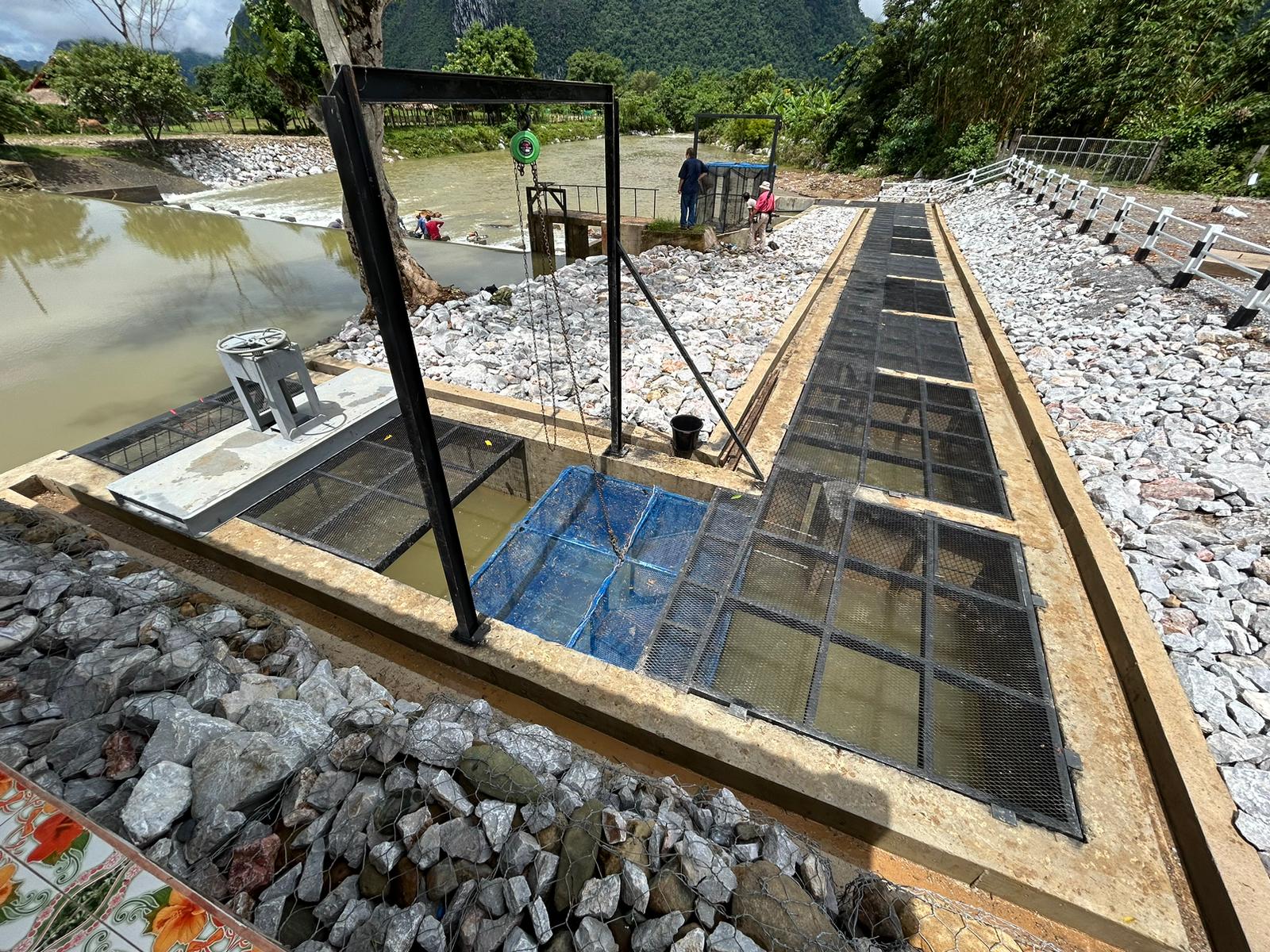 Screened water channels and infrastructure beside a riverbank.