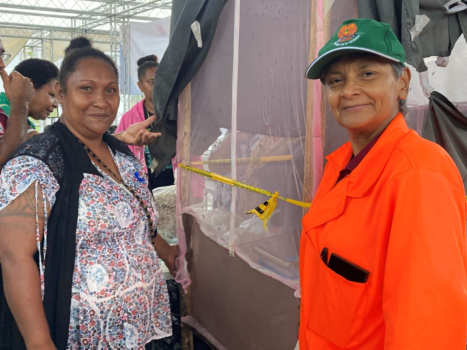 Two people standing beside an insect-screened enclosure inside a covered structure.