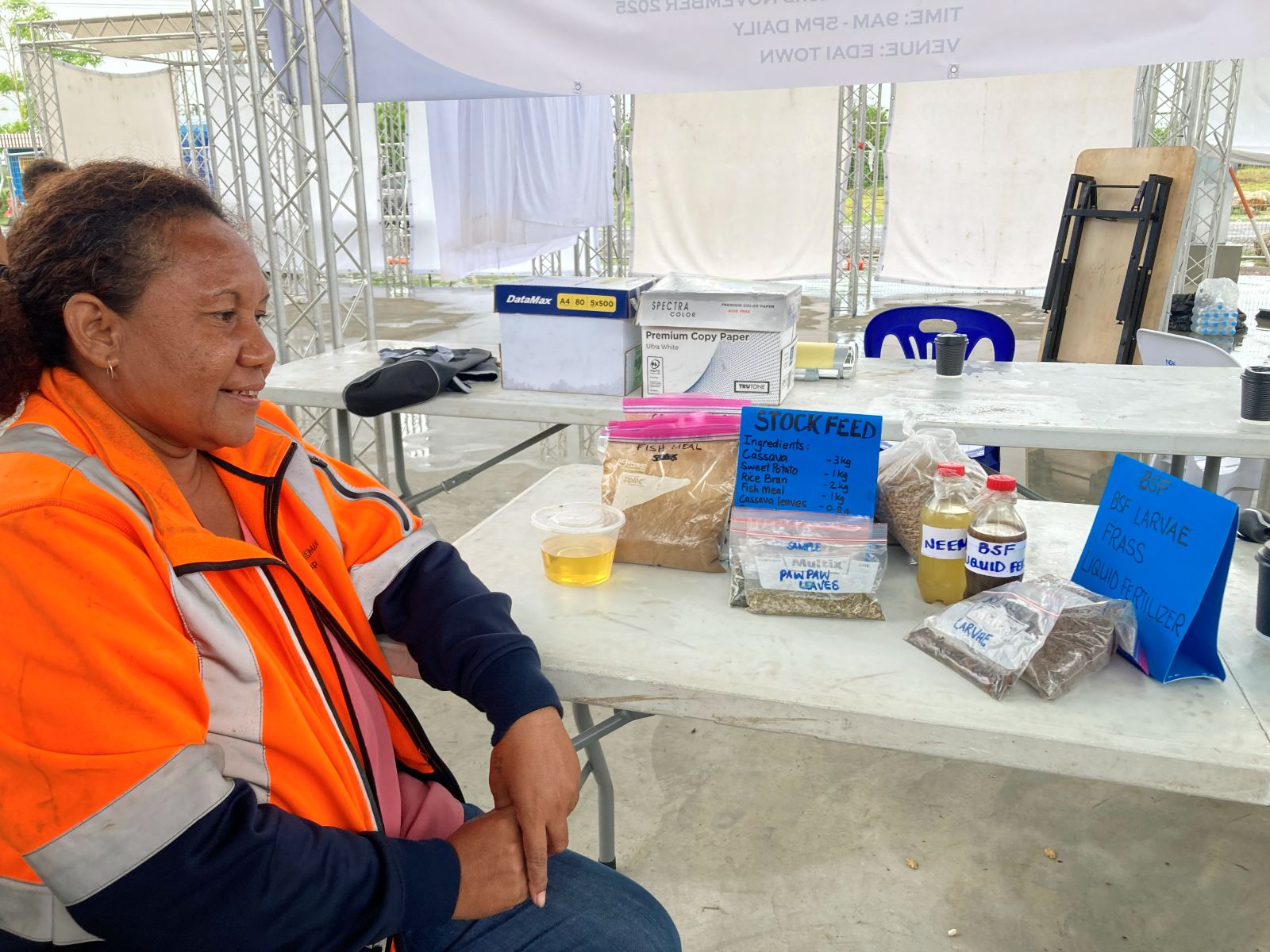 Person seated beside a table displaying packaged samples and liquids.