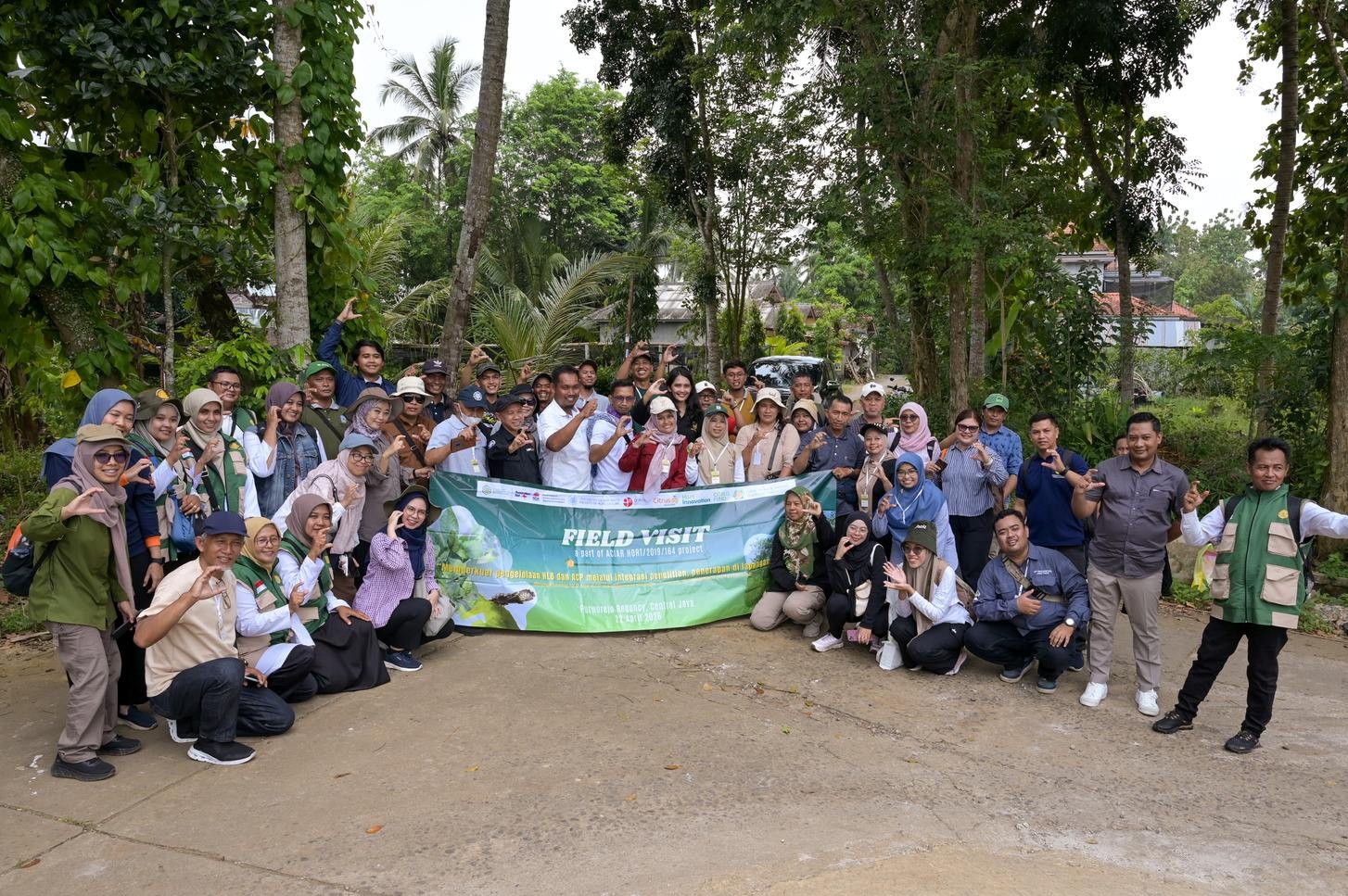 Group of participants standing outdoors holding a field visit banner.
