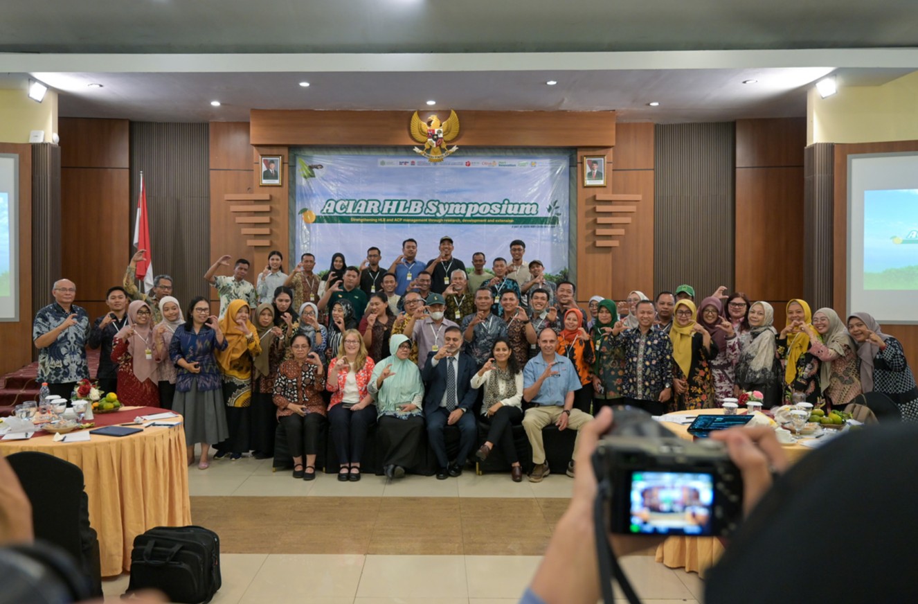 Large group photo at an ACIAR HLB symposium in a conference room.