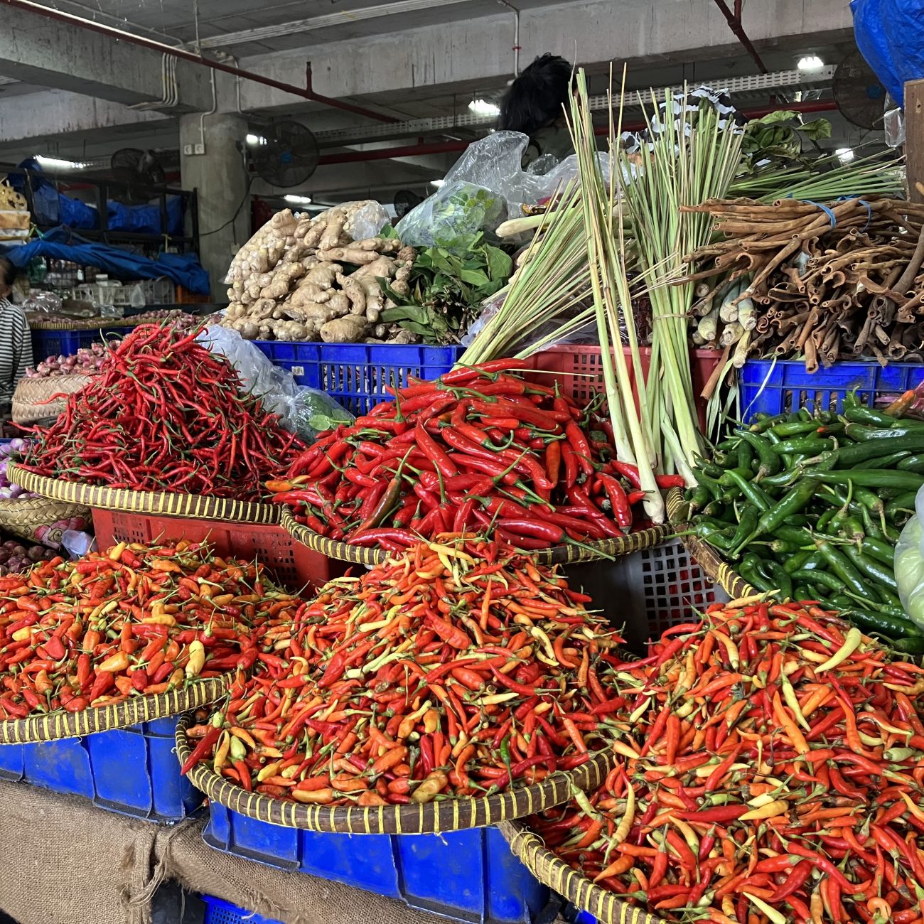 Market stall displaying baskets of fresh produce, including red and green chillies.