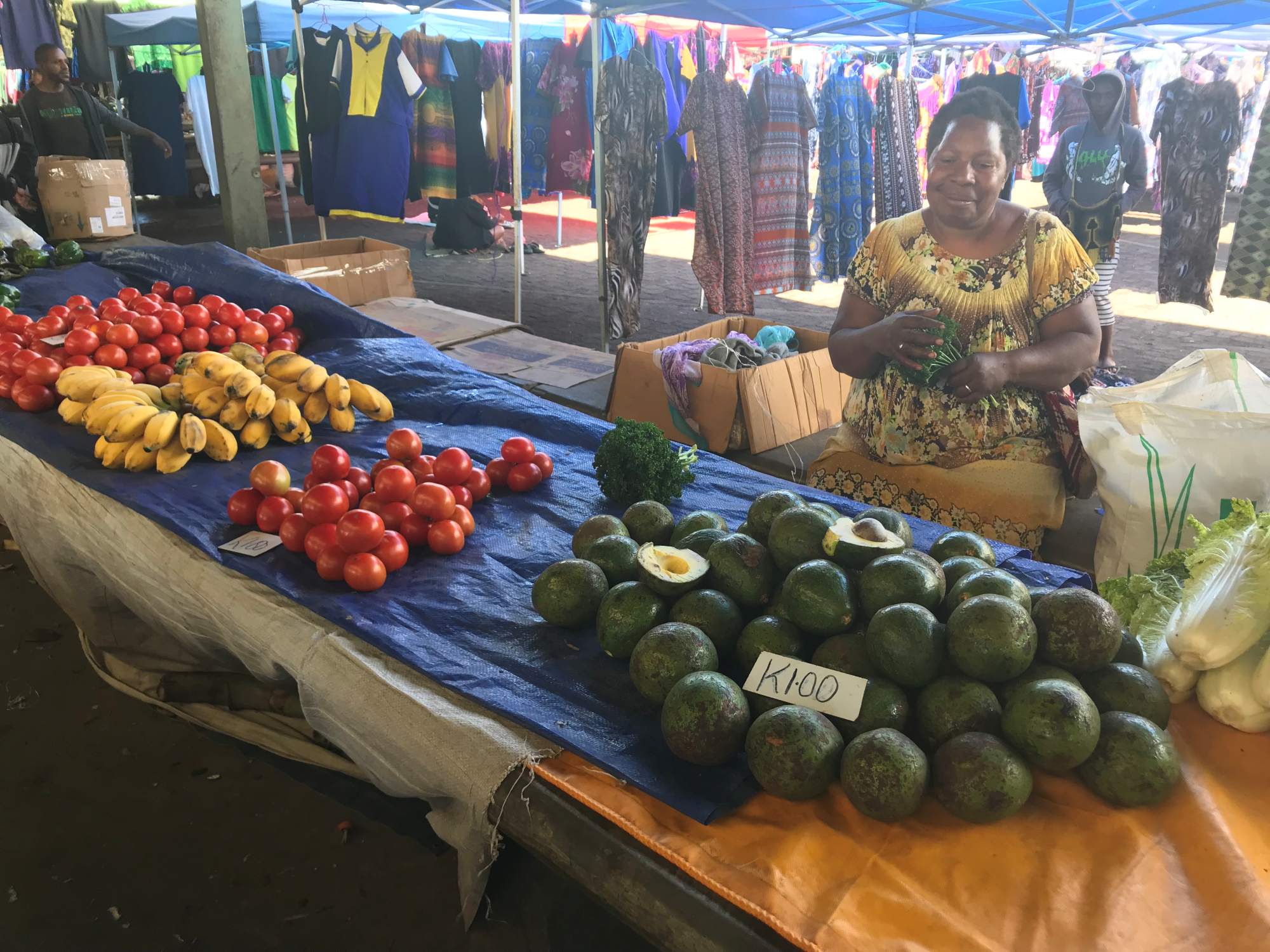 Women sitting at her market stall selling vegetables 