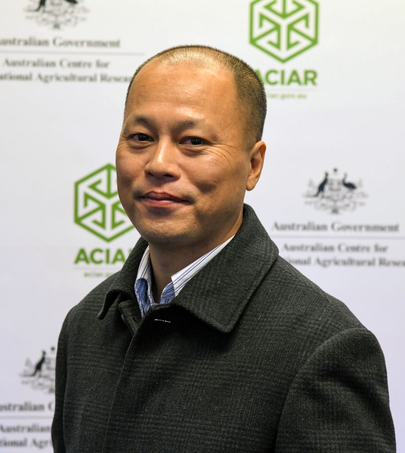 Nam Anh standing in front of an ACIAR-branded backdrop.