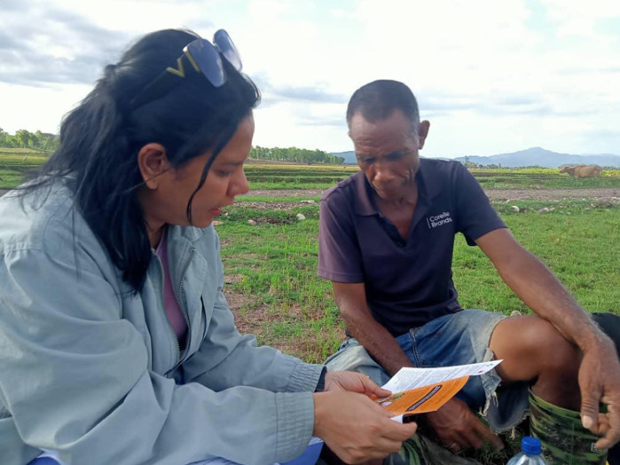 Community member and researcher review survey information together in an agricultural field.
