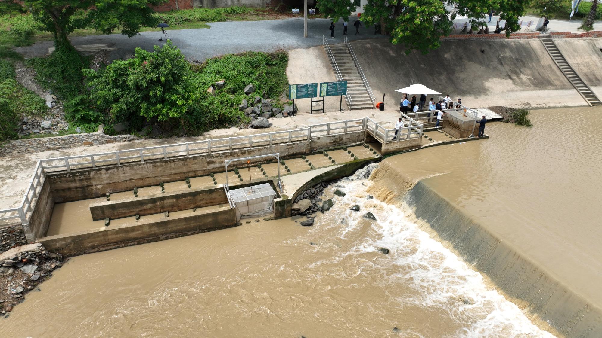 Aerial view of a water control structure and fish passage facility on a river channel.