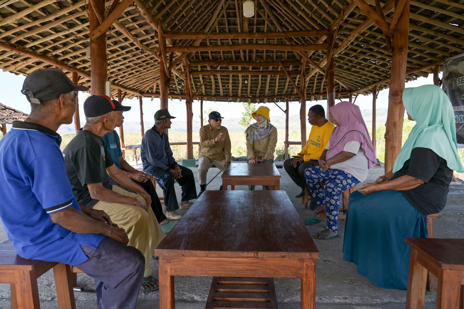 Community members and researchers meeting in an open-sided shelter to discuss local challenges and solutions.