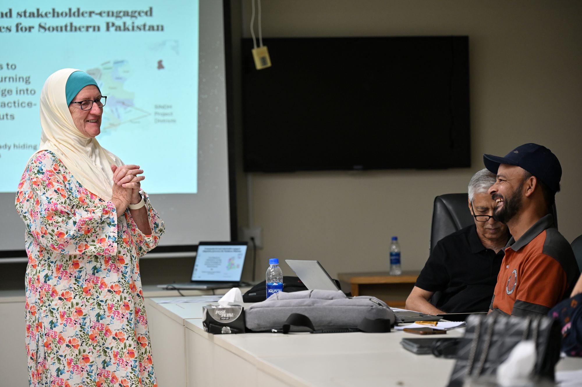 Participant speaking during a workshop while others listen around a meeting table.