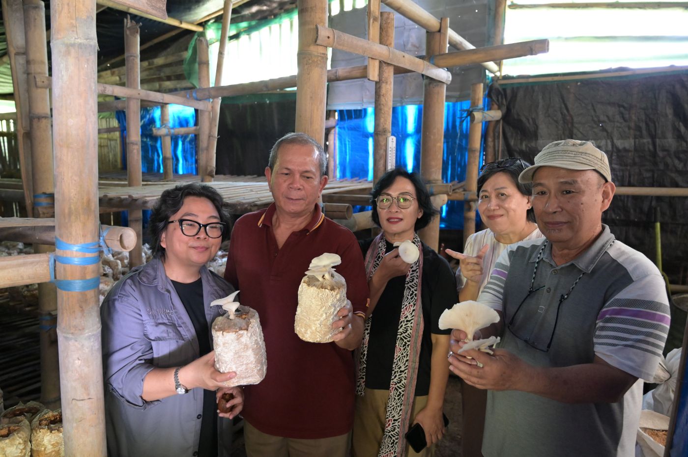 Group holding oyster mushrooms inside a mushroom farm.