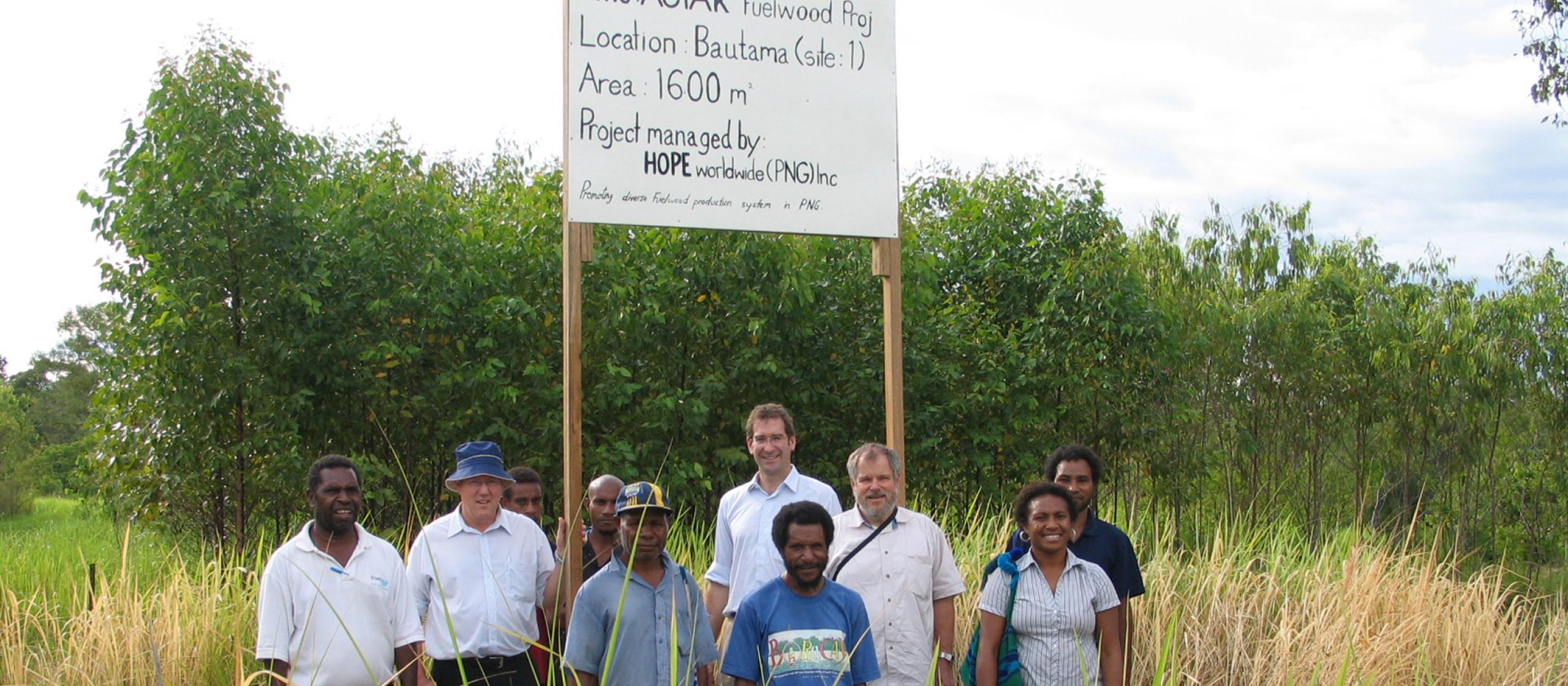 A group stands under the ACIAR Fuelwood project sign
